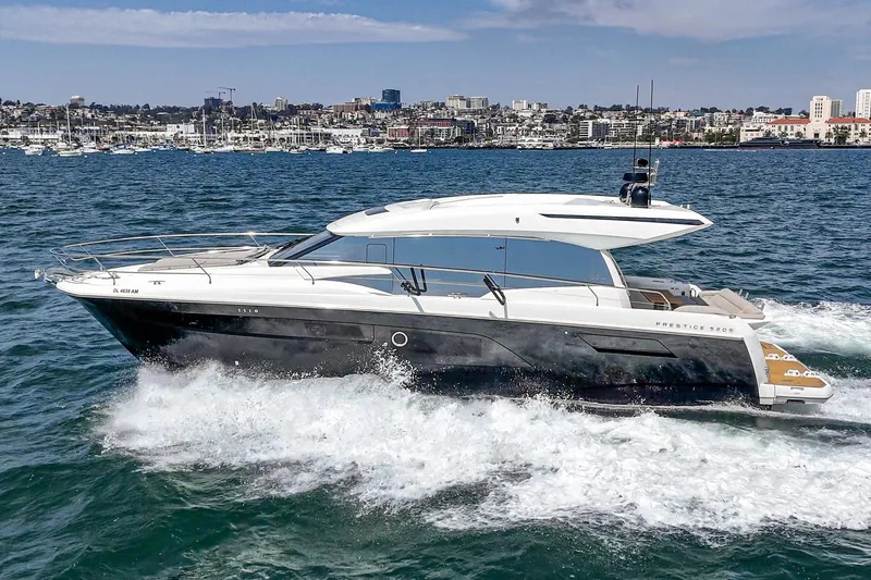 Slide: The Image of 2019 Prestige 520S yacht cruising on open water with city skyline in background. - 3