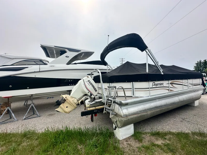 Slide: The Image of 2008 Premier 240 SunSpree pontoon boat with black canopy, parked beside a larger boat. - 11