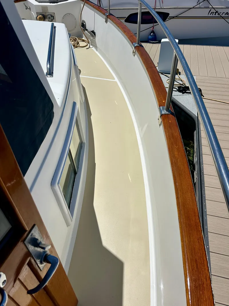 Slide: The Image of 1994 Grand Banks 42 Classic yacht deck with polished wood railing and white surface. - 15