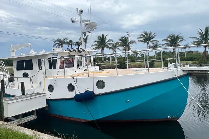 Slide: The Image of 2006 Great Harbour N37 boat docked, featuring a blue hull and white deck, with palm trees nearby. - 3