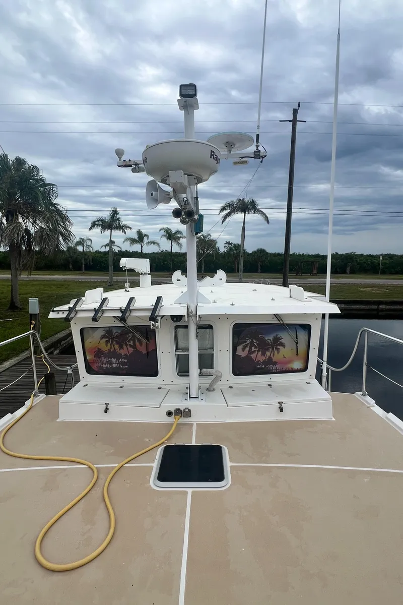 Slide: The Image of 2006 Great Harbour N37 boat with palm tree window decals, docked under cloudy skies. - 4