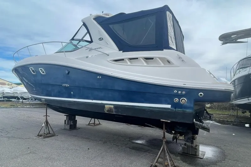 Slide: The Image of 2008 Sea Ray 330 Sundancer boat on stands, blue and white hull, outdoor setting. - 8