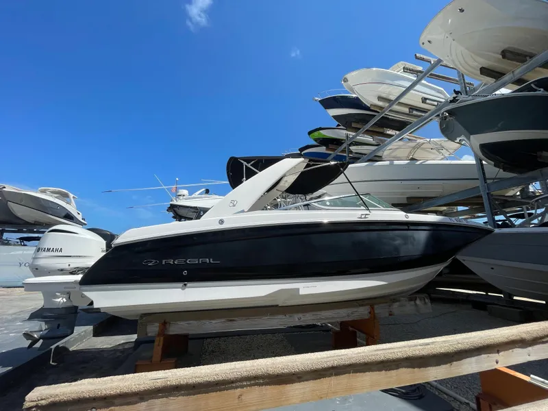 The Image of 2021 Regal 260BX boat displayed in a marina under a clear blue sky. - 0