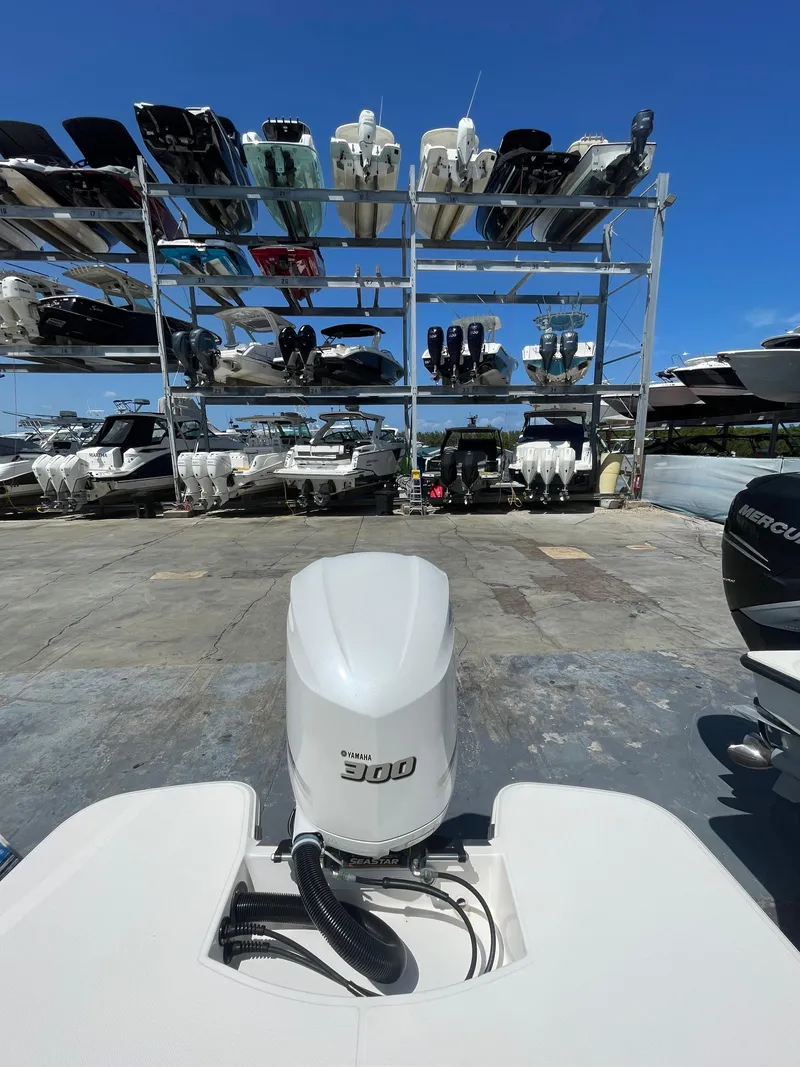 Slide: The Image of 2021 Regal 260BX boat with powerful engine, docked near stacked boats under clear blue sky. - 10