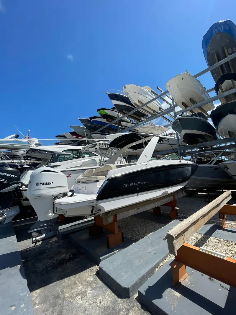 Slide: The Image of 2021 Regal 260BX boat in storage, surrounded by other vessels under a clear blue sky. - 11