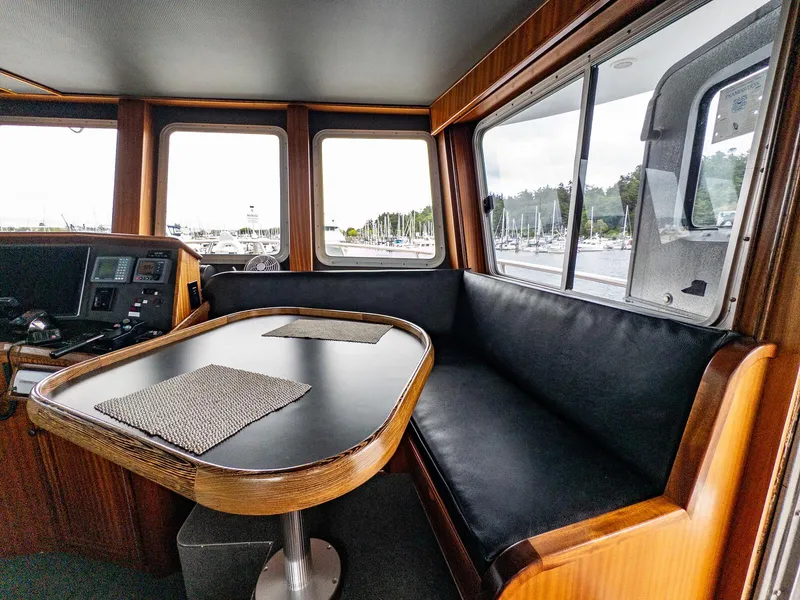 Slide: The Image of Interior of 1986 Custom Expedition Vessel 58 with seating and table, overlooking marina. - 10