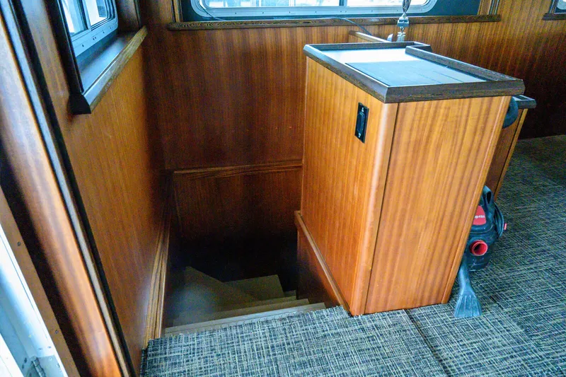 Slide: The Image of Staircase leading below deck on 1986 Custom Expedition Vessel 58, featuring wood paneling and carpeted floor. - 22