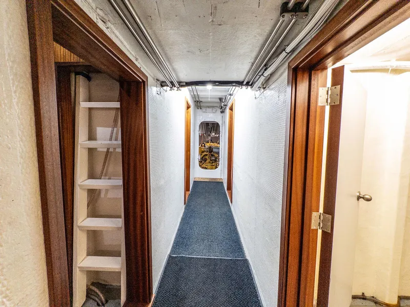 Slide: The Image of Narrow corridor inside 1986 Custom Expedition Vessel 58, featuring wooden doors and a ladder. - 23