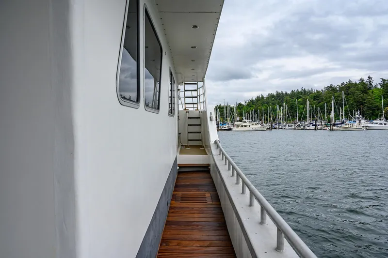 Slide: The Image of Side deck of 1986 Custom Expedition Vessel 58, overlooking marina with sailboats and cloudy sky. - 6