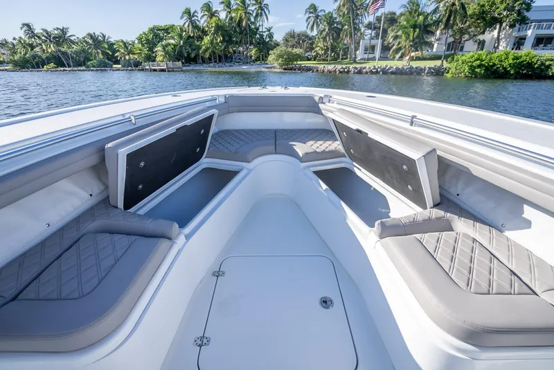 Slide: The Image of 2023 Yellowfin 36 boat interior with cushioned seating, open water, and palm trees in the background. - 38