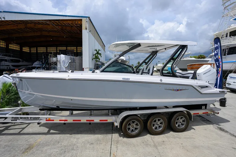 The Image of 2026 Monterey Elite 27 OB boat on trailer, parked at marina under cloudy sky. - 0
