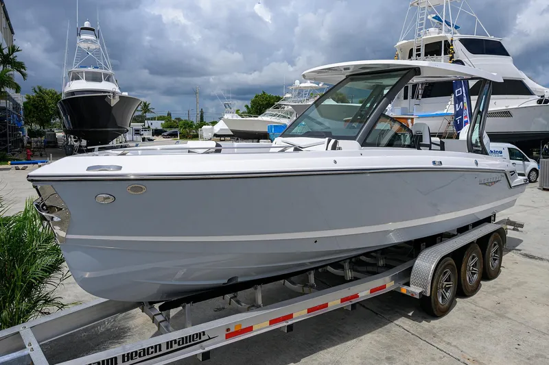 Slide: The Image of 2026 Monterey Elite 27 OB boat on trailer, docked at marina with cloudy sky. - 1