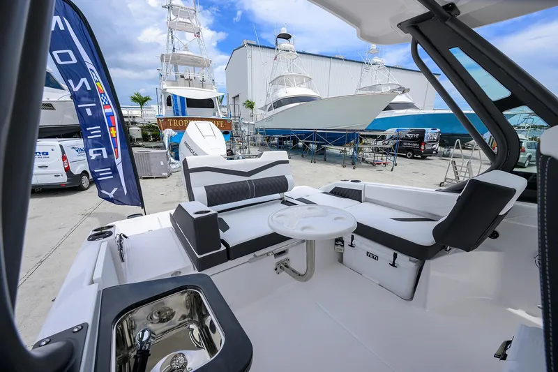 Slide: The Image of 2026 Monterey Elite 27 OB boat interior with seating, table, and marina backdrop. - 14