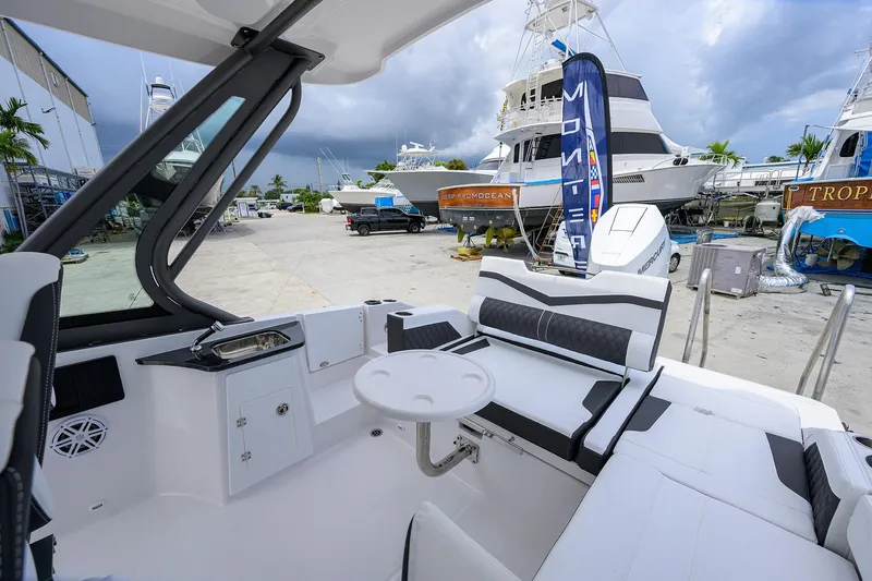 Slide: The Image of 2026 Monterey Elite 27 OB boat interior with seating and table, docked at a marina. - 15