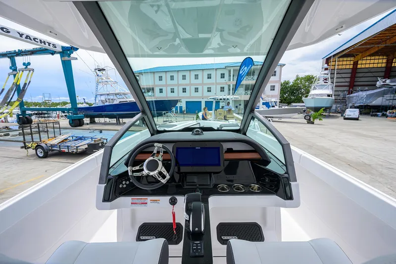 Slide: The Image of Interior view of 2026 Monterey Elite 27 OB boat at a marina, showcasing the helm and dashboard. - 18