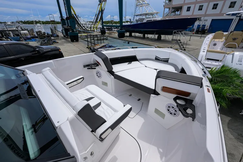 Slide: The Image of 2026 Monterey Elite 27 OB boat interior with white seating and cup holders at a marina. - 7