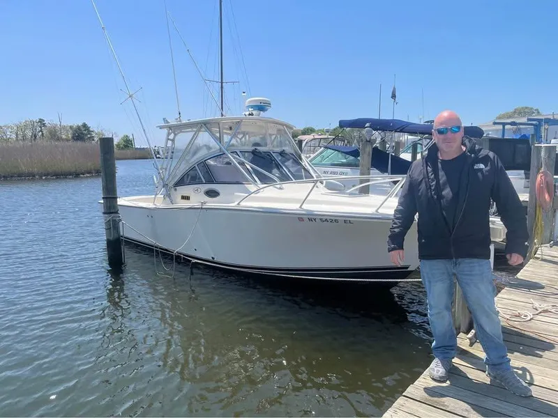 Slide: The Image of Man standing beside a 2003 Albemarle 260 boat docked in a marina. - 8