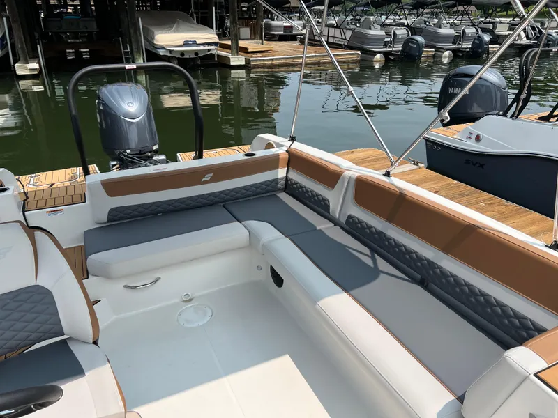 Slide: The Image of 2025 Starcraft SVX 211 OB boat interior with cushioned seating, docked at a marina. - 12
