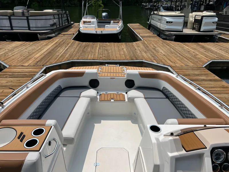Slide: The Image of 2025 Starcraft SVX 211 OB boat interior with seating, cup holders, and wooden accents at a dock. - 3