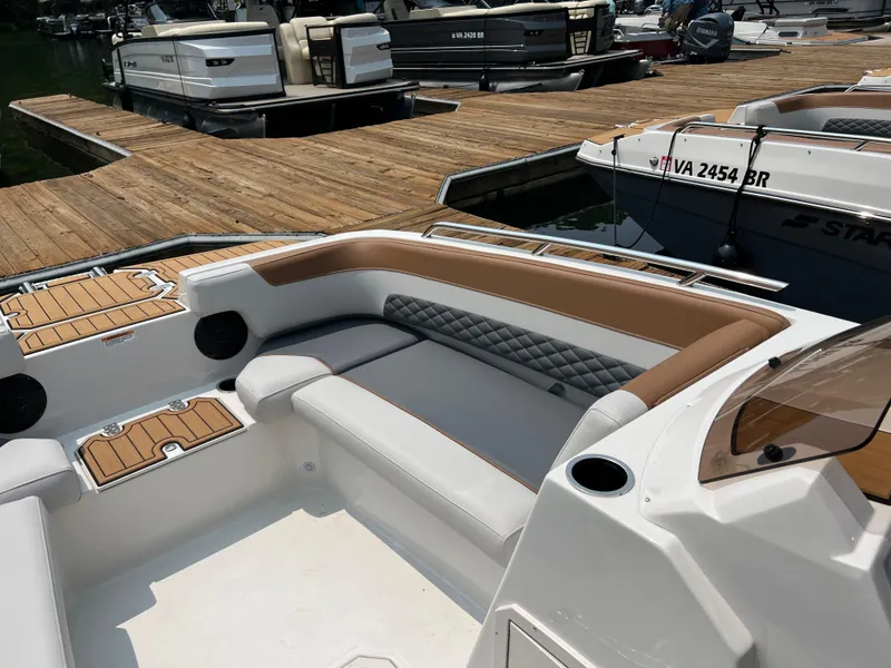 Slide: The Image of 2025 Starcraft SVX 211 OB boat interior with cushioned seating, docked at marina. - 6
