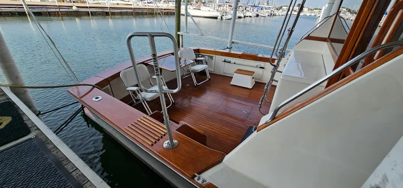 Slide: The Image of 1987 Ocean Yachts 48 Super Sport cockpit with wooden deck, chairs, and table by the water. - 14