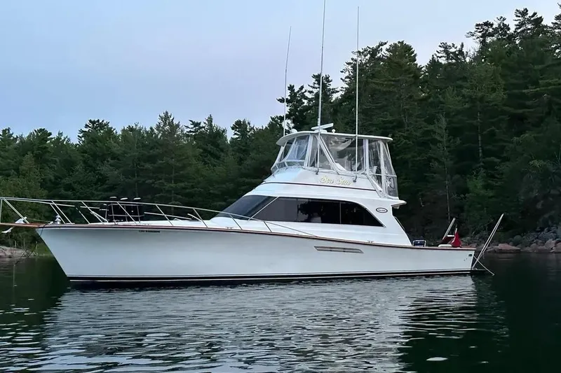 The Image of 1987 Ocean Yachts 48 Super Sport cruising on calm waters near a marina. - 0