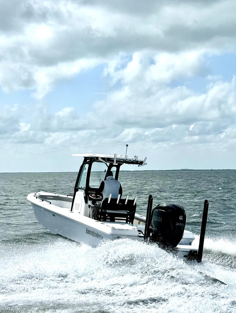 The Image of 2023 Everglades 243 CC boat cruising on open water under cloudy skies. - 1
