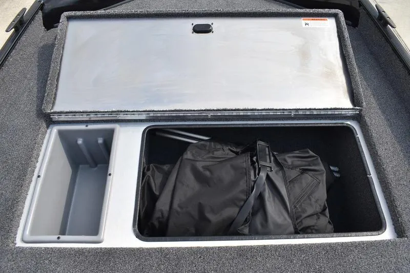 Slide: The Image of 2025 Lowe Skorpion 17 boat storage compartment with open lid and black bag inside. - 15