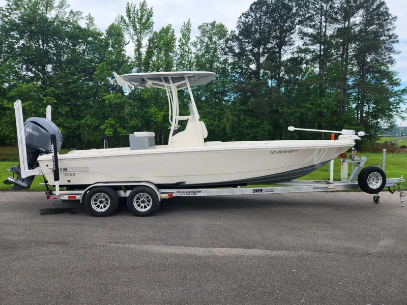 The Image of 2024 Pathfinder 2500 Hybrid boat on trailer, parked outdoors with trees in background. - 0