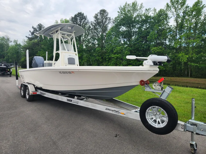 Slide: The Image of 2024 Pathfinder 2500 Hybrid boat on trailer, parked on road with green trees in background. - 1
