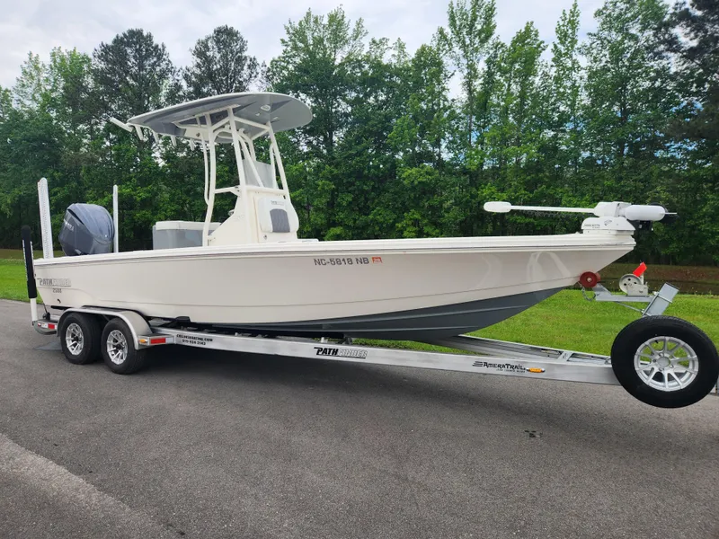 Slide: The Image of 2024 Pathfinder 2500 Hybrid boat on trailer, parked on road with trees in background. - 2