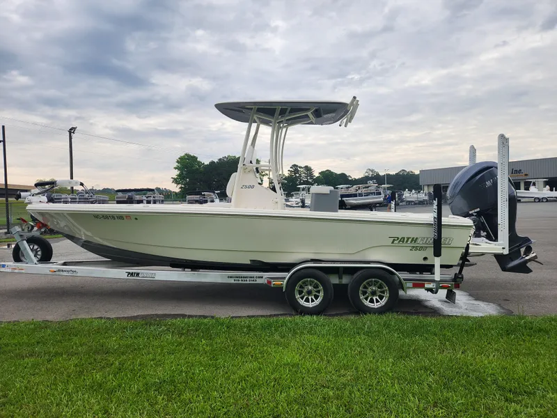 Slide: The Image of 2024 Pathfinder 2500 Hybrid boat on trailer, parked outdoors under cloudy sky. - 7