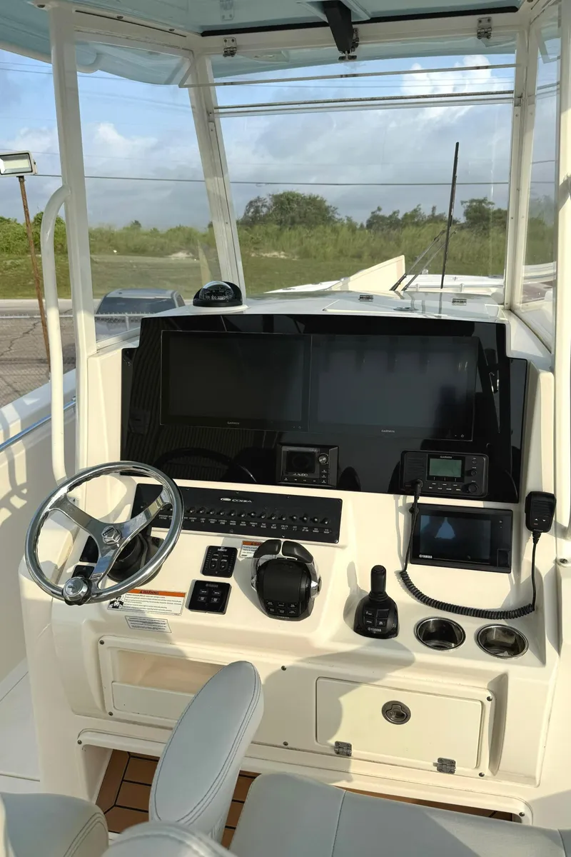 Slide: The Image of 2020 Cobia 320 Center Console boat dashboard with steering wheel and navigation equipment. - 13
