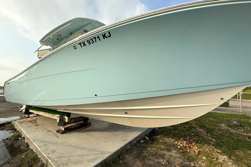 Slide: The Image of 2020 Cobia 320 Center Console boat on a stand, light blue hull, registration TX 9371 KJ. - 2
