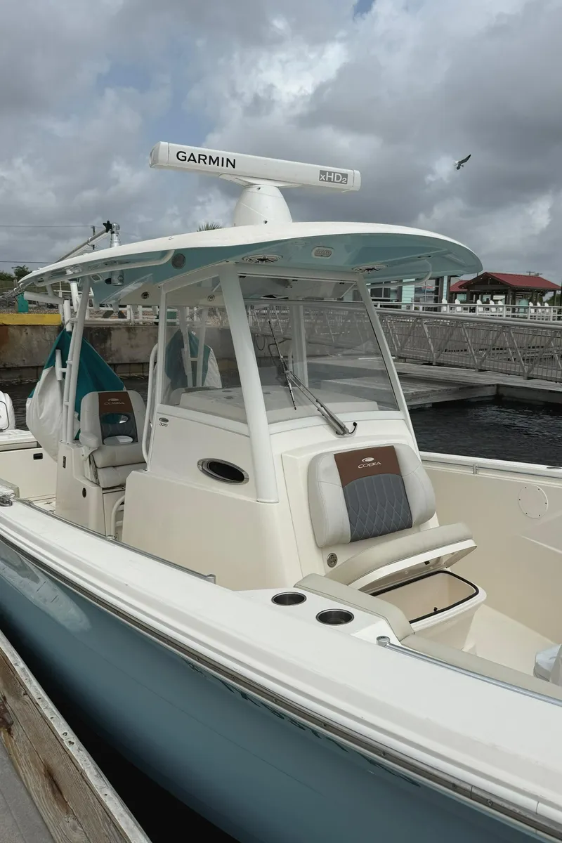 Slide: The Image of 2020 Cobia 320 Center Console boat docked, featuring Garmin equipment under cloudy skies. - 9