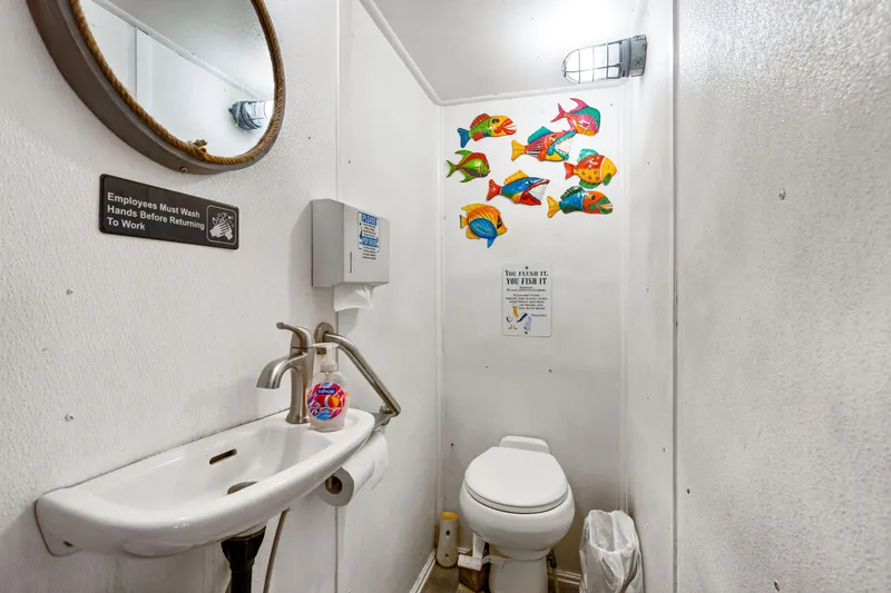 Slide: The Image of Small bathroom with colorful fish decor, mirror, sink, and toilet on a Custom Tri-Kat 60 boat. - 31