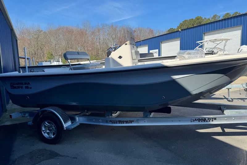 Slide: The Image of 2026 Carolina Skiff 19 LS boat on trailer, parked outdoors near blue building. - 9