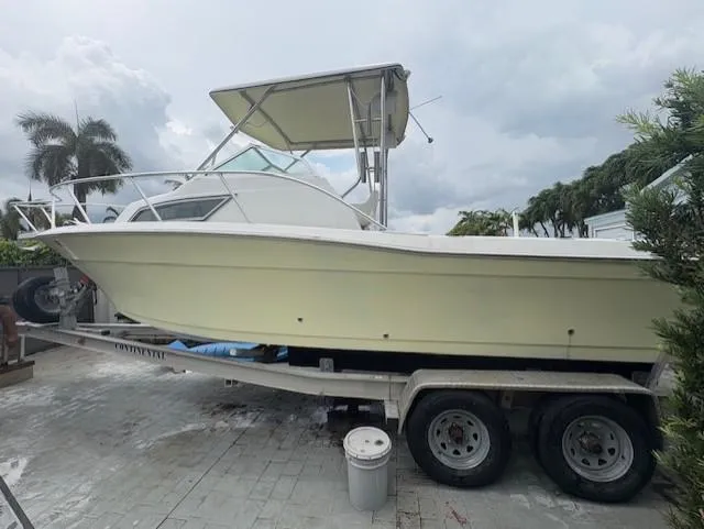 Slide: The Image of 1997 Sport-Craft 232 Sportfish boat on trailer, parked outdoors under cloudy sky. - 3