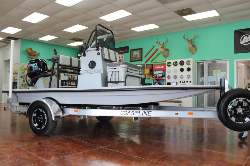 Slide: The Image of 2026 Freedom Boats Chiquita with Suzuki engine on trailer, parked outdoors. - 1