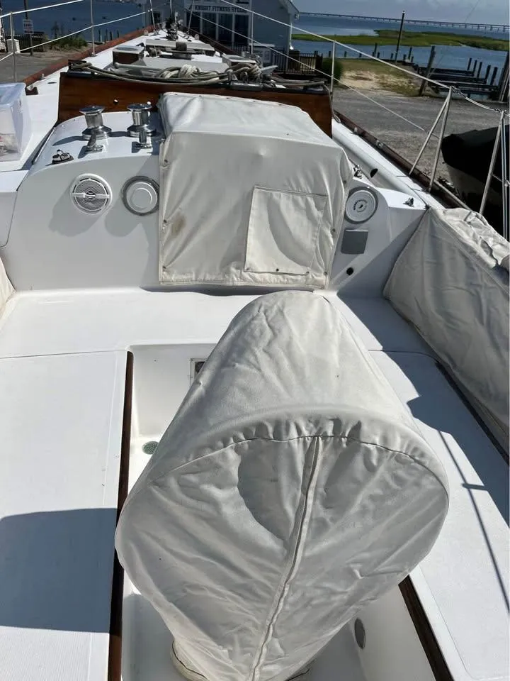 Slide: The Image of 1968 Hinckley Bermuda 40 sailboat deck with covered equipment and scenic waterfront view. - 9
