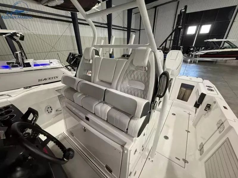 Slide: The Image of 2025 Blackfin 332 CC boat interior with modern seating and controls in a showroom. - 11