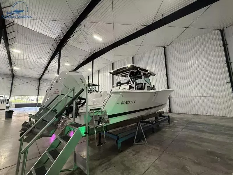 Slide: The Image of 2025 Blackfin 332 CC boat in a spacious indoor marina setting. - 2