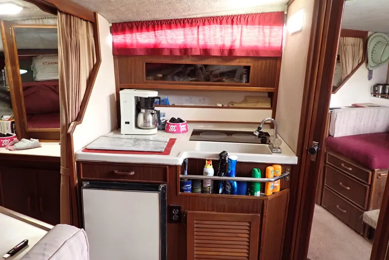 Slide: The Image of 1987 Sea Ray 300 Weekender interior with kitchenette, featuring a sink, stove, and mini fridge. - 11
