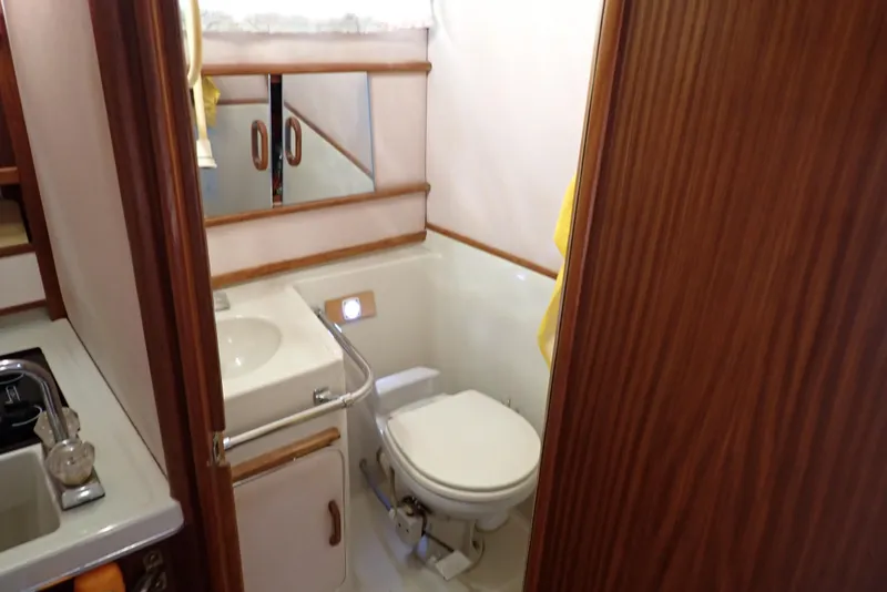 Slide: The Image of 1987 Sea Ray 300 Weekender bathroom with sink, toilet, and wooden cabinetry. - 14