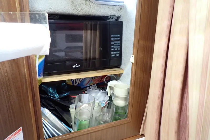 Slide: The Image of 1987 Sea Ray 300 Weekender interior with microwave and glassware storage. - 39