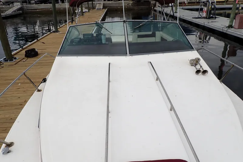 Slide: The Image of 1987 Sea Ray 300 Weekender boat docked, featuring a spacious deck and windshield. - 7