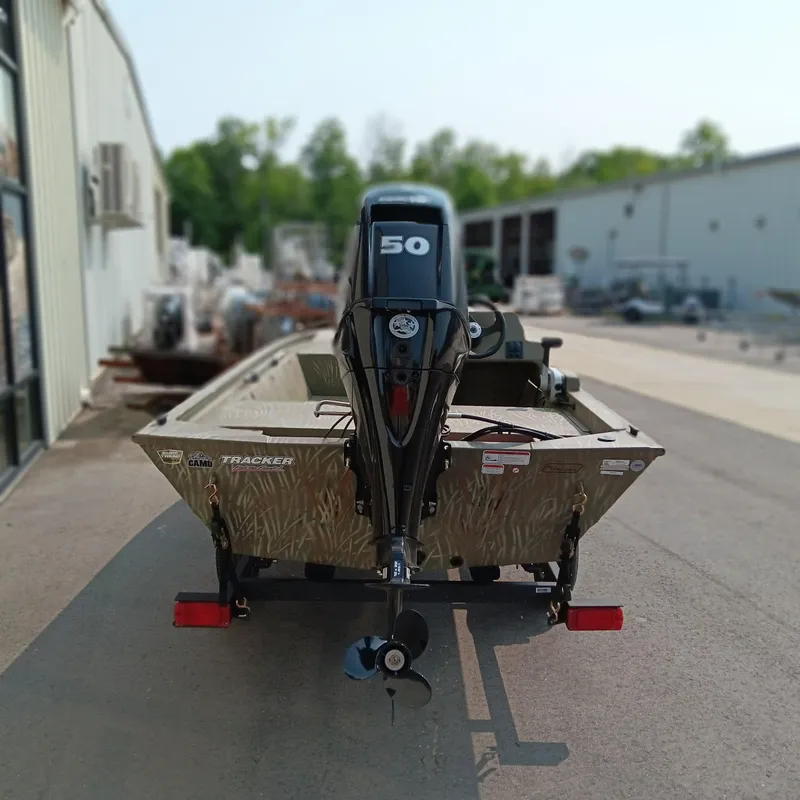 Slide: The Image of 2025 Tracker Grizzly 1648 SC boat with 50 HP motor, parked outdoors. - 3