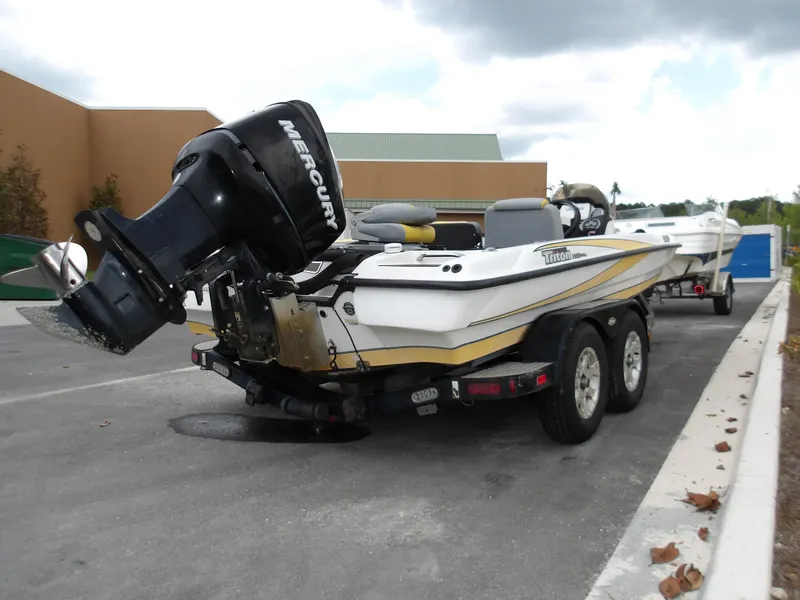Slide: The Image of 2006 Triton 20X2 boat with Mercury outboard motor on a trailer, parked outdoors. - 1