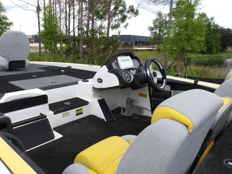 Slide: The Image of 2006 Triton 20X2 boat interior with steering wheel, seats, and dashboard in a wooded area. - 5