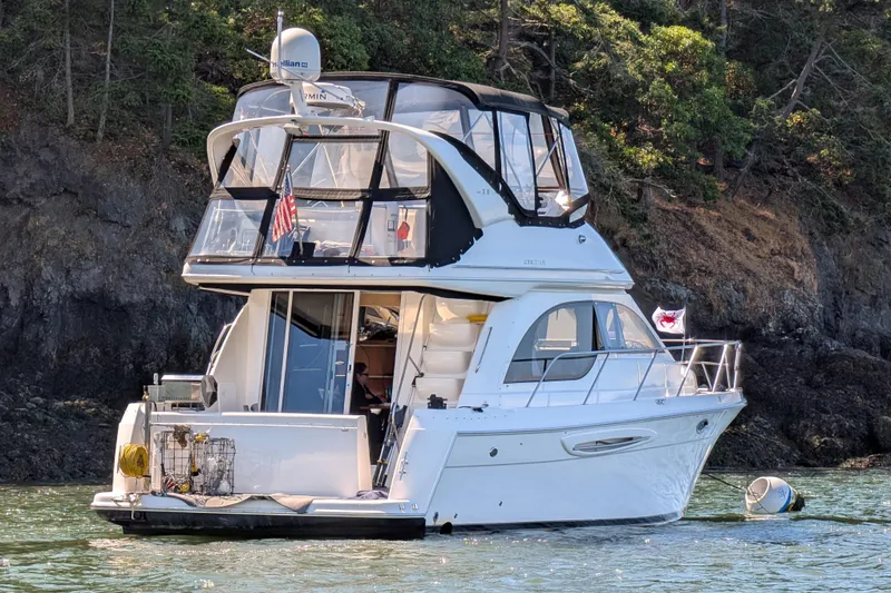 The Image of 2004 Meridian 381 Sedan yacht anchored near rocky shoreline with lush greenery. - 0
